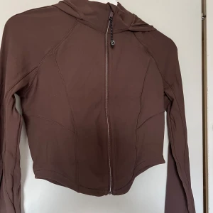 Brun hoodie med dragkedja - Säljer en brun hoodie med dragkedja framtill. Den har en snygg och enkel design med långa ärmar och en praktisk huva. Perfekt för en avslappnad stil eller träning. Materialet känns mjukt och bekvämt.