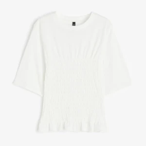 Vit topp med trekvartsärm - Säljer denna trendiga och superfina vita topp med trekvartsärm. Den är smockad i midjan och har en liten volangdetalj vid nederkanten. Perfekt för både vardag och fest! Storlek L men passar även M och ev S. Helt slutsåld på hemsidan! 