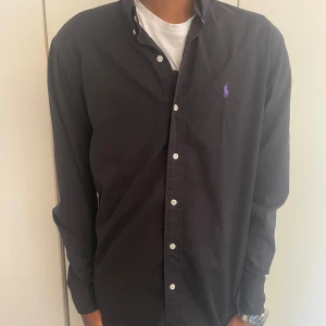 Ralph lauren strl-M - Hej! Jag säljer nu min snygga Ralph lauren skjorta i färgen svart. Den är i bra skick och väldigt snygg och stilren. Vid fler frågor och funderingar är det bara att höra av sig!