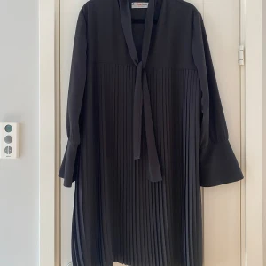 Svart plisserad klänning från Julia June i strl 42 - Svart plisserad klänning från Julia June i strl 42.  Klänningen har en fast underklänning.  Sparsamt använd och i fint begagnat skick.  Mått Över bröstet: ca 56 cm Längd från axeln och ner: ca 93 cm  100% polyester  