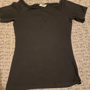 Svart kortärmad topp - Säljer en enkel och stilren svart topp med korta ärmar. Perfekt för vardagsbruk eller att klä upp med accessoarer för en festligare look. Toppen är i ett mjukt och bekvämt material. sitter tajt!