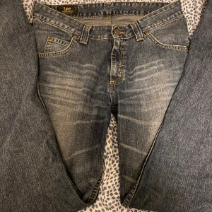 Blå jeans från Lee - Säljer ett par klassiska blå jeans från Lee. De har en snygg tvätt med lätt slitna detaljer och kontrastsömmar. Jeansen har fem fickor och en bekväm passform. Perfekta för vardagsbruk!