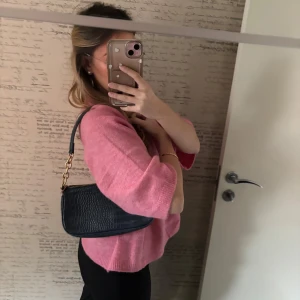 Svart axelväska med kedjedetaljer - Snygg svart axelväska i syntet med krokodilpräglat mönster och guldfärgade kedjedetaljer. 