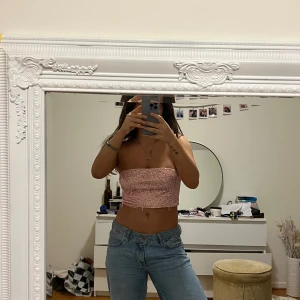 Rosa paljett tubtopp - Säljer en glittrig rosa tubtopp täckt med paljetter. Perfekt för en festlig look. Toppen är axelbandslös och har en tight passform.