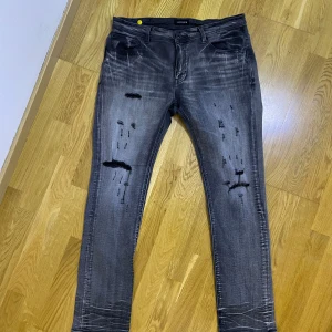 Grå jeans med slitningar - OBS: Pris kan diskuteras samt vid snabb affär kan sänkas pris.                                Snygga grå jeans med coola slitningar på framsidan. De har en klassisk femficksdesign och en knappgylf. Perfekta för en avslappnad stil. Passar killar som gillar fixa still som är topp klass och inga vanliga basic jeans.