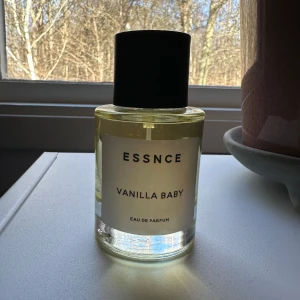 Essnce Vanilla Baby Eau de Parfum - Säljer en flaska Essnce Vanilla Baby Eau de Parfum. Doften har en söt och krämig vaniljton. Flaskan är genomskinlig med en enkel vit etikett och svart kork. Perfekt för dig som älskar varma och inbjudande dofter.