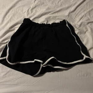 Svarta shorts med vit kant - Snygga svarta shorts med vit kant. Perfekta för en avslappnad stil. Elastisk midja för bekväm passform.