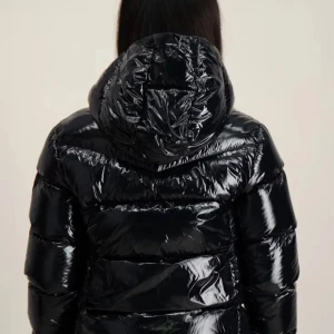 Svart glansig dunjacka från Colmar - Snygg svart glansig dunjacka från Colmar med huva och dragkedja framtill. Jackan har en quiltad design och långa ärmar, perfekt för kyliga dagar. Använt få gånger. Pris kan diskuteras