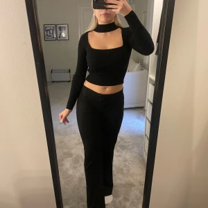 Svart ribbad croppad topp - Snygg svart långärmad ribbad topp med halschoker, från bershka. Använd ca 3 gånger så ser helt ny ut!! Hör av dig för frågor🥰