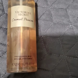 Coconut Passion Fragrance Mist från Victoria's Secret - Säljer en Coconut Passion Fragrance Mist från Victoria's Secret. Denna doftspray har en exotisk doft av kokos och vanilj. Flaskan är genomskinlig med en gyllene vätska och rymmer 250 ml. Perfekt för att ge en fräsch och tropisk känsla.