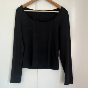 Svart långärmad topp - Snygg svart långärmad topp med en enkel och stilren design. Perfekt för att matcha med olika outfits. Toppen har en rund halsringning och är tillverkad i ett mjukt material.