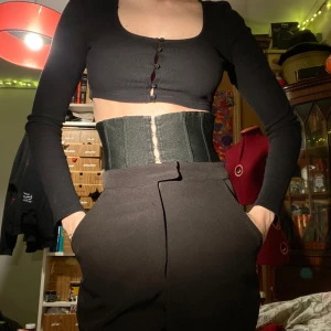 Svarta långa TALL byxor från Missguided med korsett - Förjävligt långa byxor från Missguided med hög knäppningsbar midja och gylf. Får inte ens plats i bild. För folk med långa ben (: 88cm innerbenslängd och ca 32cm midebredd. Ingen aning varför jag köpte dem för de är verkligen långa. Stl S-M (midjekorsetten är alltså en del av byxorna)