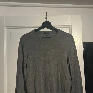 Grå tröja från Uniqlo - Säljer en stilren grå tröja från Uniqlo. Tröjan har en rund halsringning och långa ärmar, perfekt för en minimalistisk look. Passar bra till både jeans och chinos. Tröjan är lite norpig men ingen annat.
