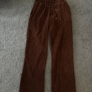 Bruna manchesterbyxor med snörning - Snygga bruna manchesterbyxor med snörning i midjan och praktiska fickor. Byxorna har en avslappnad passform och är perfekta för en stilren look. De är tillverkade i mjukt manchestertyg som ger en skön känsla.