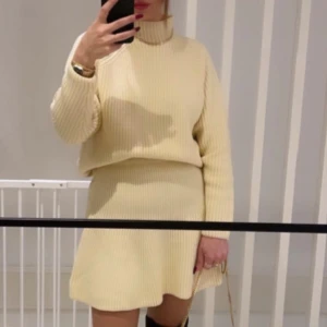 Beige ribbad klänning - Snygg beige ribbad klänning med långärmad topp och kort kjol. Perfekt för en stilren look med en mysig känsla. Den har en hög krage och en avslappnad passform som ger en chic touch.