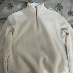 Vit fleece tröja med dragkedja - Säljer en mysig vit fleece tröja med halv dragkedja. Perfekt för kyliga dagar med sin mjuka och varma känsla. Tröjan har långa ärmar och en hög krage för extra värme. Passar bra till både vardag och avslappnade stunder. Pris kan diskuteras!!