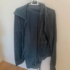 Mjuk grå velourjacka - Säljer ett supermjukt set. Jackan har en avslappnad passform och långa ärmar, perfekt för mysiga dagar. Den har också praktiska fickor på sidorna. Perfekt för att hålla sig varm och bekväm. Byxorna har mudd nertill, m i båda delarna