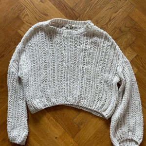 Vit stickad croppad tröja - Säljer en vit stickad tröja med en croppad, lös passform. Tröjan har långa ärmar och ett luftigt stickat mönster som ger en avslappnad look. 
