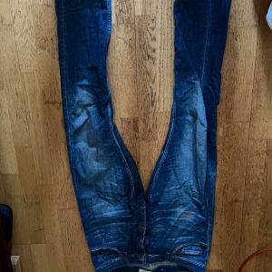 Blå jeans från Tiger of Sweden stl 32/36 - Snygga blå jeans från Tiger of Sweden i modellen Pistolero. De har en klassisk design med dragkedja och knapp framtill. Perfekta för en stilren look.