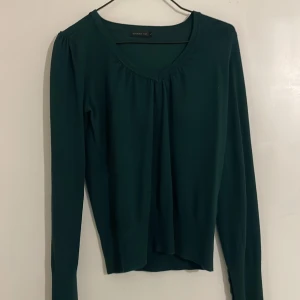 Grön långärmad topp - Snygg grön långärmad topp med v-ringad design. Perfekt för en stilren look. Passar bra till både jeans och kjol. Enkelt att matcha med andra plagg i garderoben.
