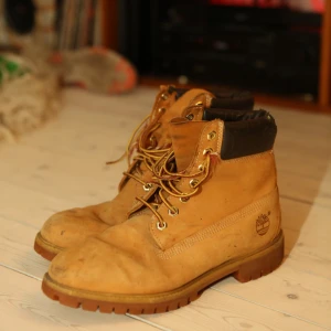 Bruna boots från Timberland - Säljer ett par klassiska bruna boots från Timberland med snörning och vadderad krage. Perfekta för höst och vinter med sin robusta design och slitstarka material.