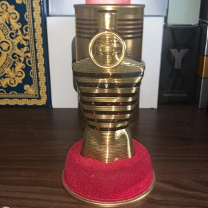 Jean Paul Gaultier Le Male Elixir Parfym - Exklusiv parfym i en elegant guldfärgad flaska formad som en manlig torso. Flaskan har horisontella ränder och en distinkt ringdetalj på korken. Förpackningen är en matchande guldfärgad metallburk med märkets logotyp och parfymens namn ingraverat. Säljer för 500 eftersom att den är lite använd men priset kan diskuteras, är även öppen för byten!