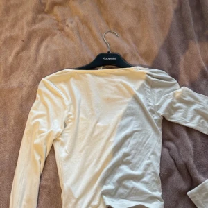 Vit långärmad topp från Nelly  - Säljer en stilren vit långärmad topp från Nelly. Toppen har en v-ringad design med snygg rynkning framtill som ger en fin detalj. Perfekt för en chic och enkel look.