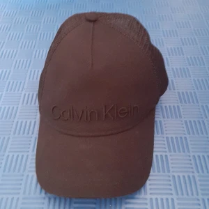 Svart keps från Calvin Klein - Snygg svart keps från Calvin Klein med broderad logga framtill. Kepsen har ett nätmaterial på baksidan för bättre ventilation och justerbart spänne för perfekt passform.