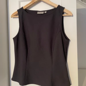 Mörkgrå ärmlös topp från Hennes Collection - Snygg svart ärmlös topp från Hennes Collection. Kostymaktig topp som passar perfekt för en stilren look. Mörkgrå