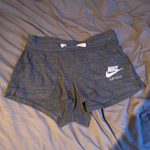 Grå shorts från Nike - Säljer ett par grå shorts från Nike. De har en bekväm passform med snörning i midjan och resår. 