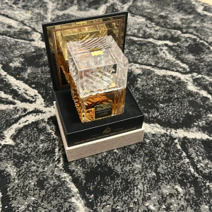 Khamrah Eau de Parfum från Lattafa - Elegant parfymflaska med ett kristalliknande mönster och gyllene detaljer. Doften Khamrah från Lattafa kommer i en lyxig förpackning med svart och guld. Perfekt för den som söker en sofistikerad och unik doftupplevelse.
