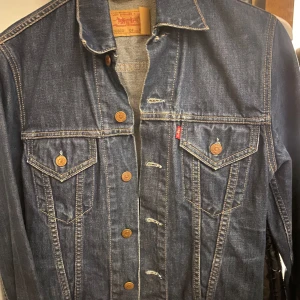 Jeansjacka från Levi Strauss & Co. - Klassisk jeansjacka från Levi Strauss & Co. i blå denim med knappar framtill och två bröstfickor med knappstängning. Perfekt för våren