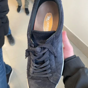Svarta sneakers från Getflex - Snygga svarta sneakers från Getflex i mocka med snörning. Perfekta för en stilren look. Skorna har en vit sula som ger en fin kontrast till det svarta.