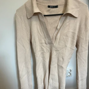 Beige ribbad tröja från Gina Tricot - Säljer en stilren beige ribbad tröja från Gina Tricot. Tröjan har en klassisk krage och långa ärmar, perfekt för en avslappnad men ändå elegant look. Passar bra till både jeans och kjol. Perfekt för höst och vår! Finns en liten fläck på (se bild) som jag inte har provat att få bort 🤍