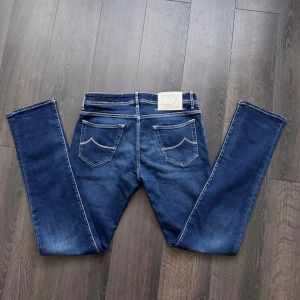 Blå jeans från Jacob Cohën - (Säljs för lägre än inköpspris) Snygga blå jeans från Jacob Cohën med klassisk femficksdesign och kontrastsömmar. De har en knappgylf och är perfekta för en avslappnad stil. Märkeslappen baktill ger en extra touch.