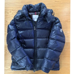 Mörkblå dunjacka från Moncler  - Säljer en snygg mörkblå dunjacka från Moncler. Storlek m, Använd fåtal gånger stilren design med Moncler-logga på ärmen. Kvitto finns. Helt äkta, priset är inte hugget i sten 