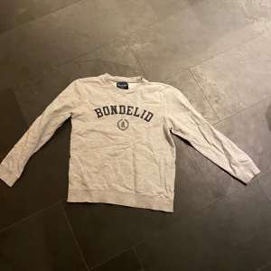 Grå sweatshirt från Bondelid - Säljer en stilren grå sweatshirt från Bondelid med tryck på bröstet. Storlek S