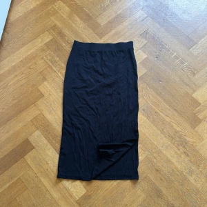 Svart långkjol från 157 - Säljer en stilren svart långkjol från märket 157. Kjolen är i storlek S och har en ribbad struktur som ger en snygg och bekväm passform. Perfekt för både vardag och festliga tillfällen!🖤