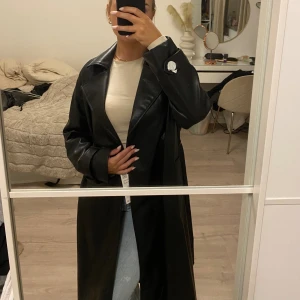 Lång skinnkappa  - Lång svart skinnkappa från Zara med knytband runt midjan. Aldrig använd och slutsåld på hemsidan, perfekt till hösten. Kommer med prislapp och skyddande papper runt knappar.