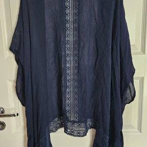 Marinblå kimonoblus L/XL - En mycket fin marinblå kimonoblus i viskos med virkad spets och kort ärm. Storlek L/XL.