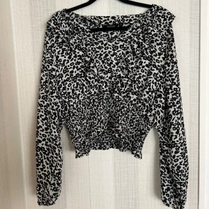 Loopars blus  - Snygg topp med leopardmönster och volangdetaljer. Toppen har en elastisk resår i midjan.