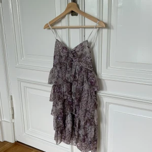 Blommig klänning med volanger - Säljer en superfin blommig klänning med volanger. Den har tunna justerbara axelband och en härlig, luftig passform. Perfekt för höstens alla fester! 💜