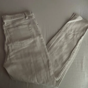 Beige byxor - Säljer ett par snygga vita byxor. De har en klassisk femficksdesign med knapp och dragkedja framtill. Perfekta för en avslappnad men stilren look!