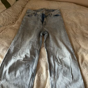 Ljusblå jeans från Monki - Säljer ett par ljusblå jeans från Monki i storlek 28. De har en klassisk femficksdesign och är tillverkade i 100% bomull. Jeansen har en straight passform och är perfekta för en avslappnad stil. De är i bra skick och redo för en ny ägare!