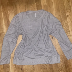 Grå stickad tröja - Säljer en supermysig grå stickad tröja som är perfekt för kyliga dagar. Den har en normal passform med långa ärmar och ribbade muddar vid ärmslut och nederkant. Tröjan är enkel och stilren, vilket gör den lätt att matcha med olika outfits. Perfekt för både vardag och mysiga hemmakvällar!