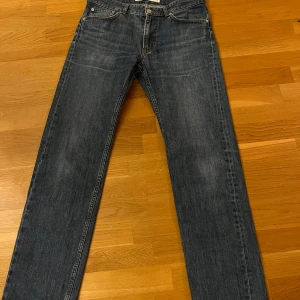 Blå jeans - Säljer ett par klassiska blå jeans i normal passform. De har en rak stil och är perfekta för vardagsbruk. Jeansen har en traditionell femficksdesign och stängs med dragkedja och knapp. De är i bra skick och redo för en ny ägare! märket är Lacoste och är W 32 L 34. modelln är 180 cm 