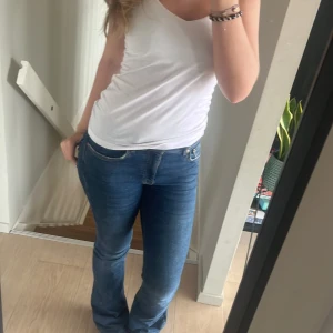 Lågmidjade jeans från Gina tricot - Säljer ett par snygga blå jeans från gina tricot i storlek 36. De har en klassisk design med en bekväm passform och är perfekta för vardagsbruk. Jeansen har en knapp och dragkedja framtill och är i ett mjukt denimtyg. Använd några gånger men inte längre eftersom dem är lite för små. Lite slitna längst ned på byxorna men det är inget som märks❤️