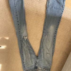 Levis 512 Bootcut Jeans - Säljer ett par Levis 512 bootcut jeans i en ljusblå tvätt. De har en klassisk femficksdesign och är lite slitna vid knäna för en cool, vintage look. Perfekta för en avslappnad stil!