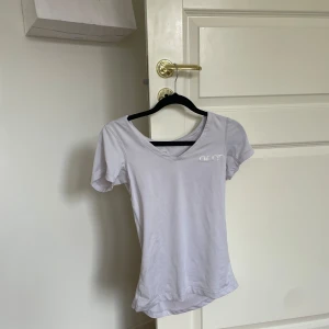 Vit t-shirt från Aim'n - Säljer en vit t-shirt från Aim'n i storlek XS. Den är gjord av mjukt och bekvämt material, perfekt för träning eller vardagsbruk. T-shirten har en v-ringad hals och korta ärmar. Den är i bra skick och redo för nya äventyr!