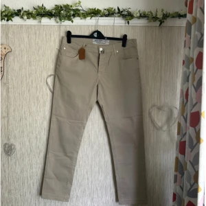 Beige byxor från Jacob Cohen - Säljer ett par snygga beige byxor från Jacob Cohen. De är handgjorda i italien och är Perfekta för både vardag och lite mer uppklädda tillfällen. Byxorna är i storlek 35 och har en normal passform. Köpta för 3799